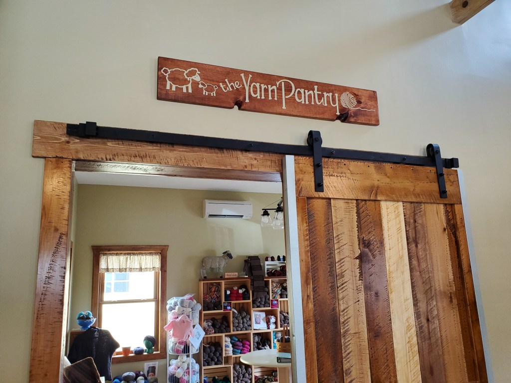 Sign that says "The Yarn Pantry" over a barn door
