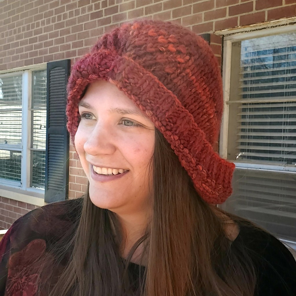Emma modeling the red She's a Betty Bonnet with the brim rolled up