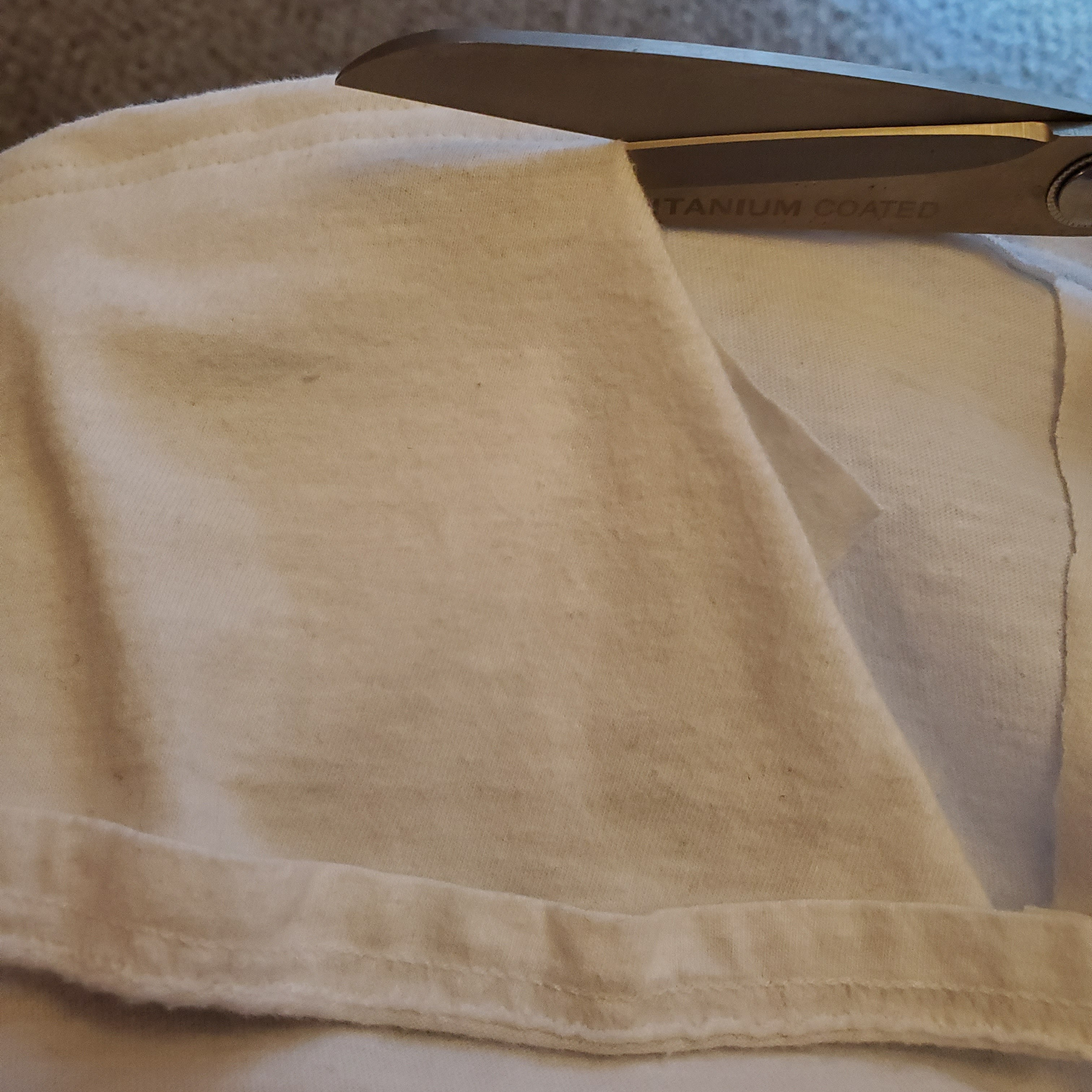 Scissors cutting away part of the shirt