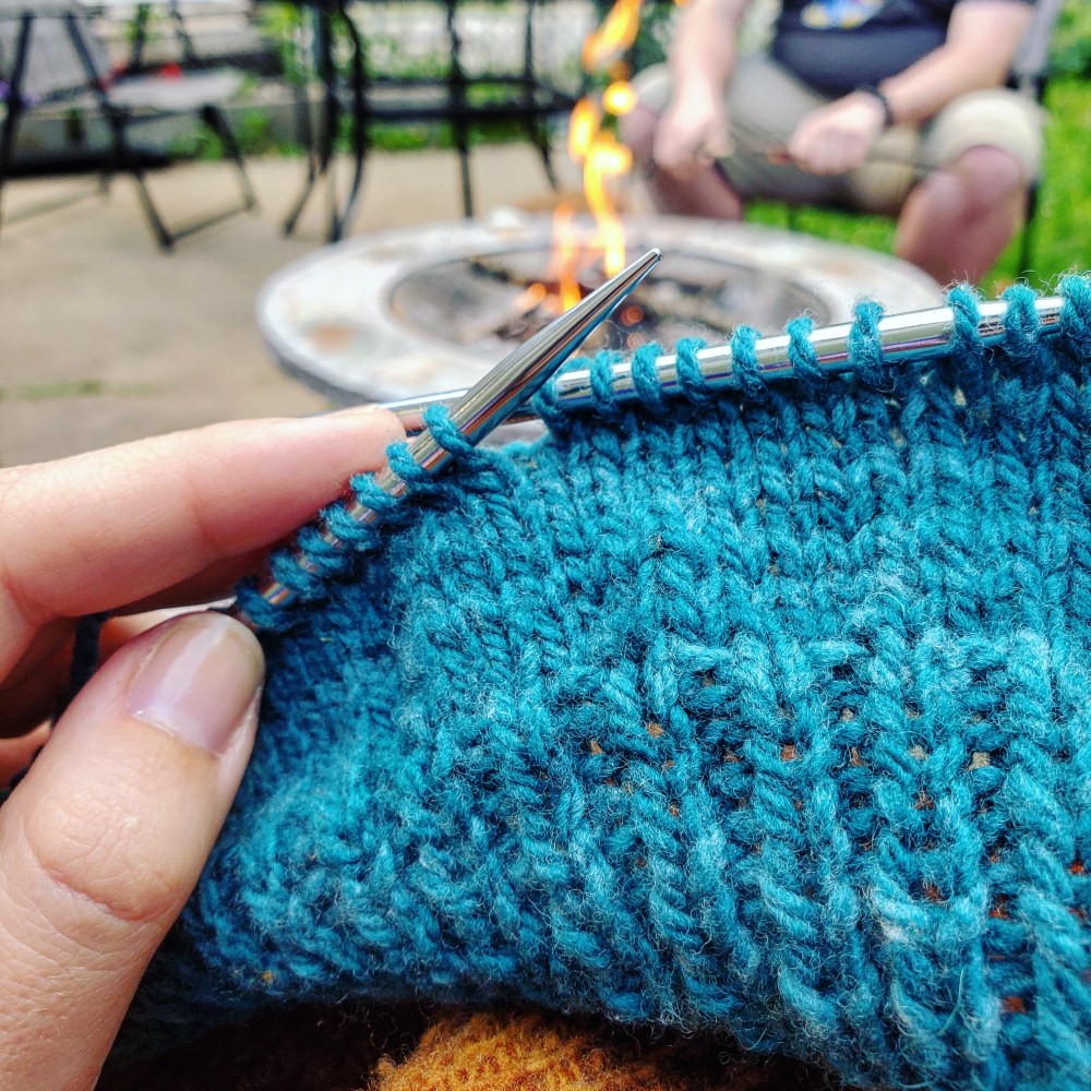 Blue knitting project in front of a fire