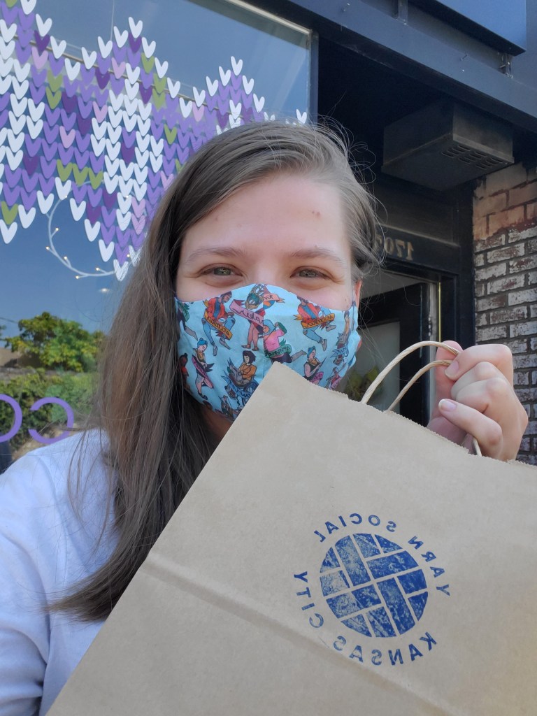 Emma holding a Yarn Social shopping bag outside of the store