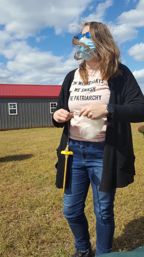 Emma, masked, spinning on a farm. Her shirt reads "On Wednesdays, we smash the patriarchy"
