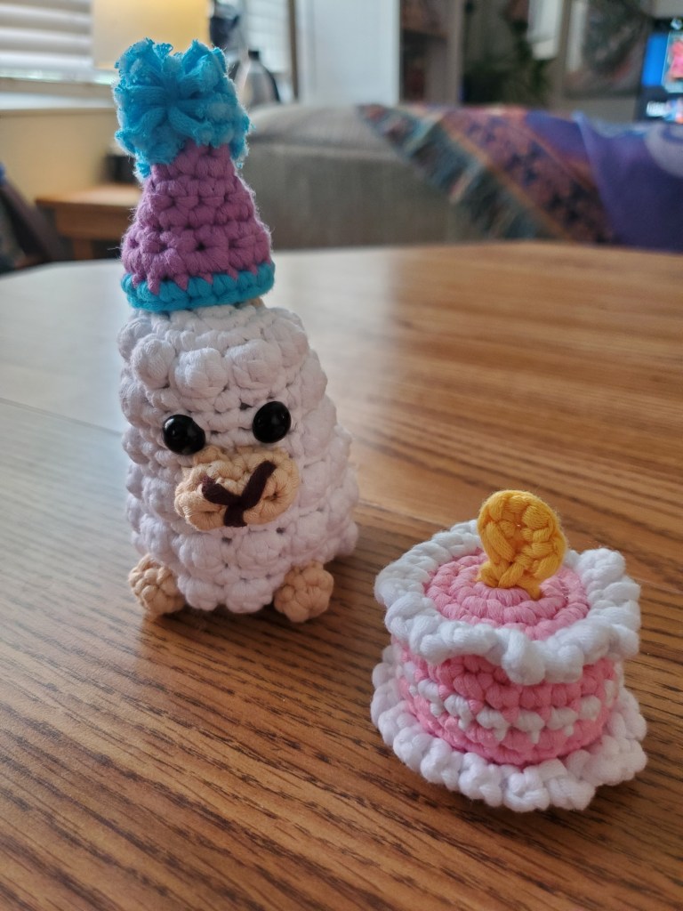 Crocheted Llama Wooble with a party hat and birthday cake