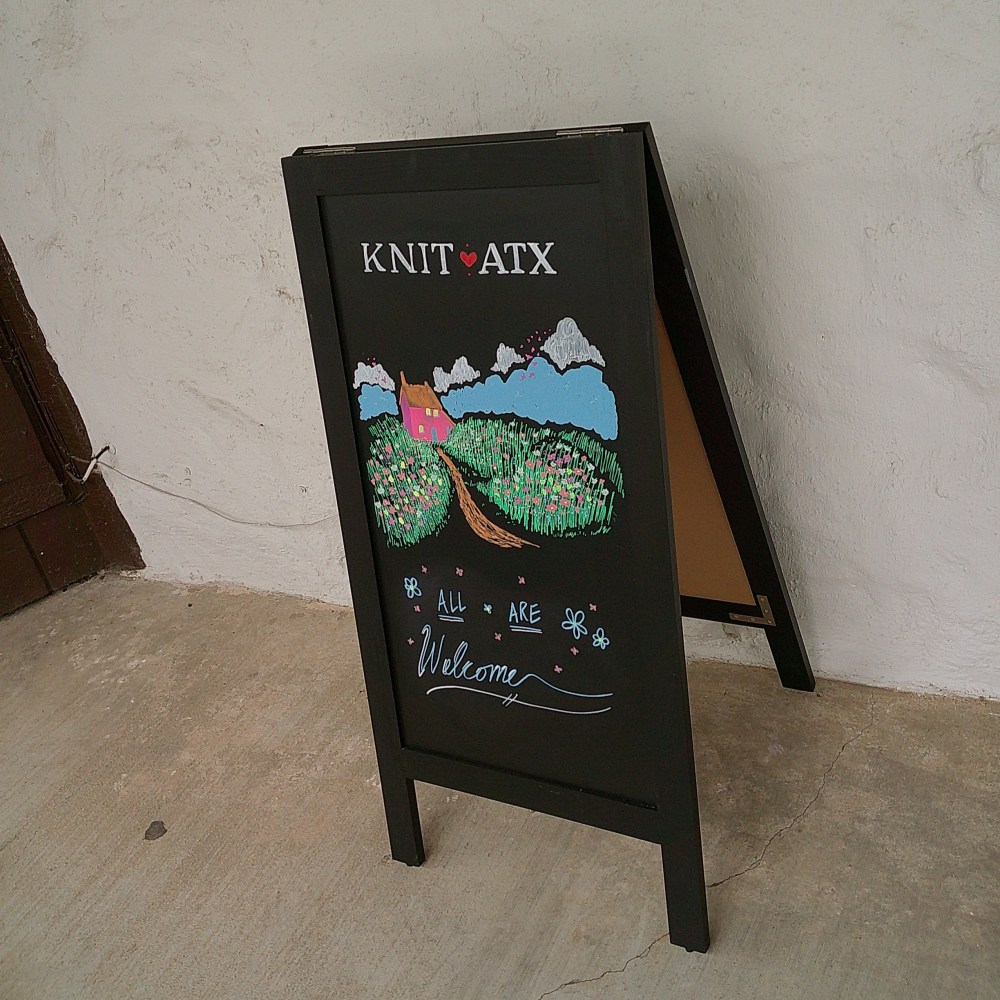 Knit ATX sign, with "All are Welcome" at the bottom
